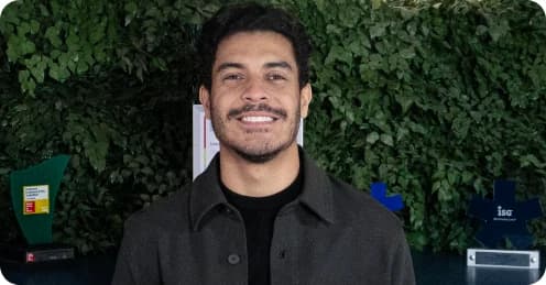 Higor Granero, Head de Inovação, diante de uma parede verde com troféus